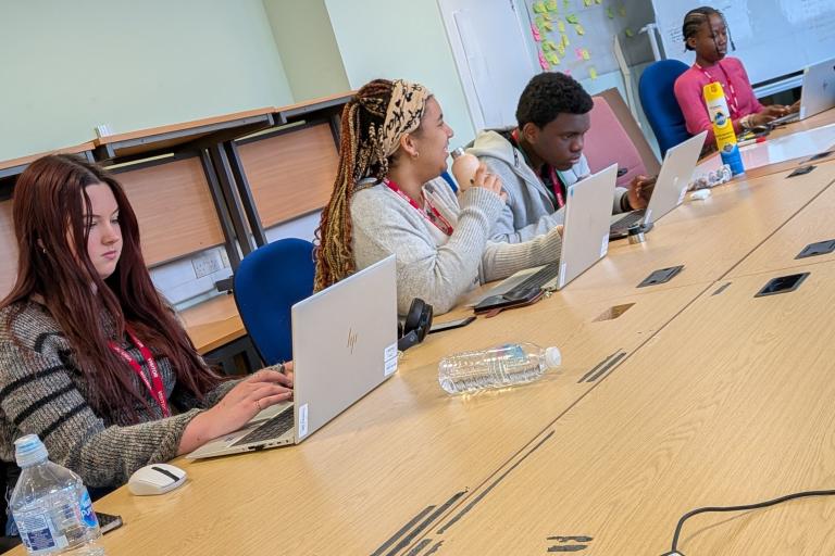 Students working on laptops and whiteboards in a bright, modern Council office