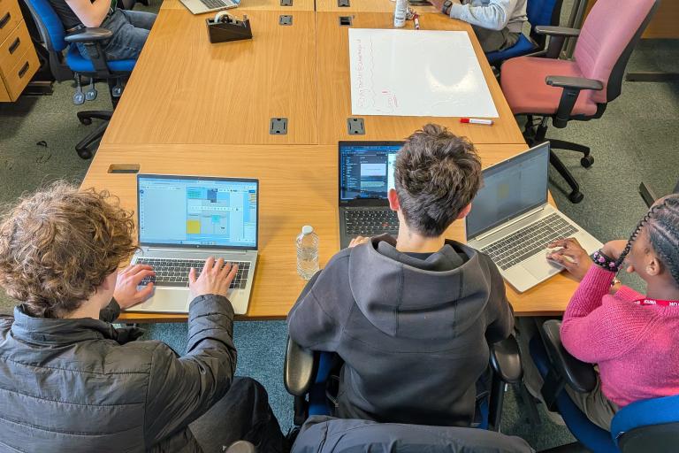 A high angle view of three students working on laptops