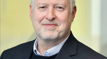 A picture of a man in a suit poses for a picture.